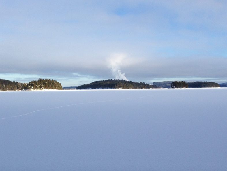 Revsundssjön, som på ngåot vis är lite lik Väsman i Ludvika. Stor sjö med blå höjder runtomkring. Det som ser ut som en rykande vulkan är bara rykande vattenånga från Gällösågens tork. 